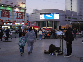 man signing and playing guitar at Culture Square in Mudanjiang, China