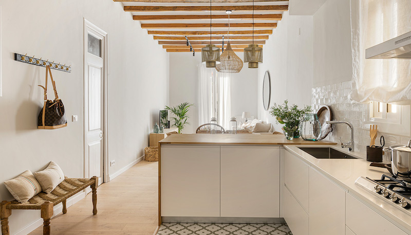 La reforma integral de un encantador piso de 90 metros Cocina open concept abierta al salón con barra alta de madera