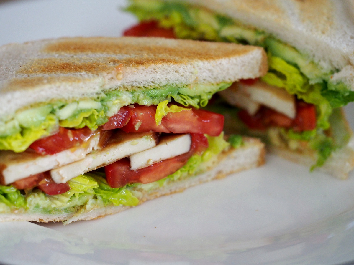 Zwei Hälften des Avocado-Tofu Sandwiches auf einem Teller