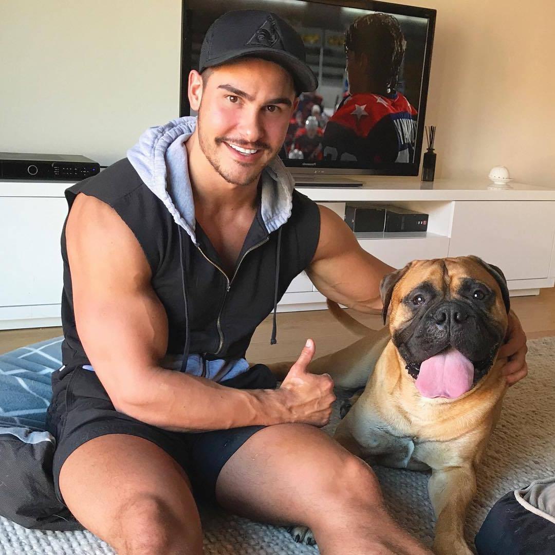 handsome-dude-big-biceps-dog-pet-tongue-watching-sports-game-thumbs-up-smiling-mustache