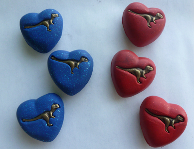 red and blue heart-shaped magnets with a dinosaur in the center of each