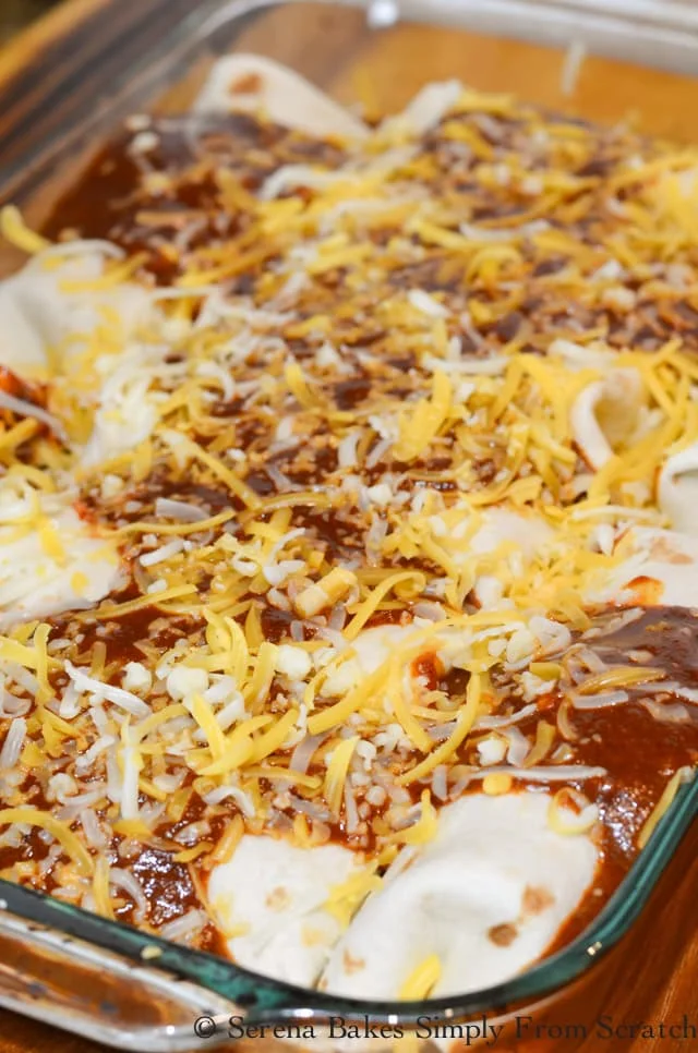 Steak Burritos covered with homemade enchilada sauce and shredded yellow and white cheese.