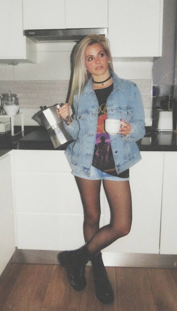 Estilo grunge con camiseta negra ancha con imagen del grupo The Doors, pantalón corto, medias de red pequeña, botas estilo militar y cazadora vaquera