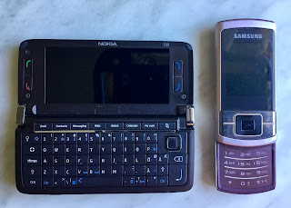 Nokian kommunikaattori ja Samsungin liukuläppäpuhelin avattuna niin, että niiden näppäimistö on esillä.
