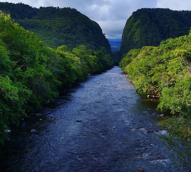 río cristalino con dos montañas verdes al fondo