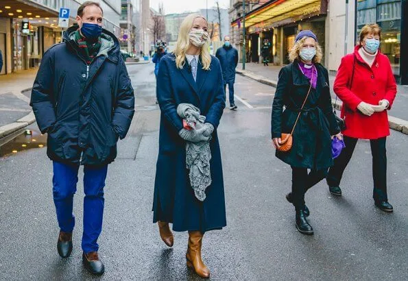 Crown Princess Mette-Marit wore a navy blue wool cashmere coat and camel leather boot. Peter Pan collar blue and white blouse with gingham check