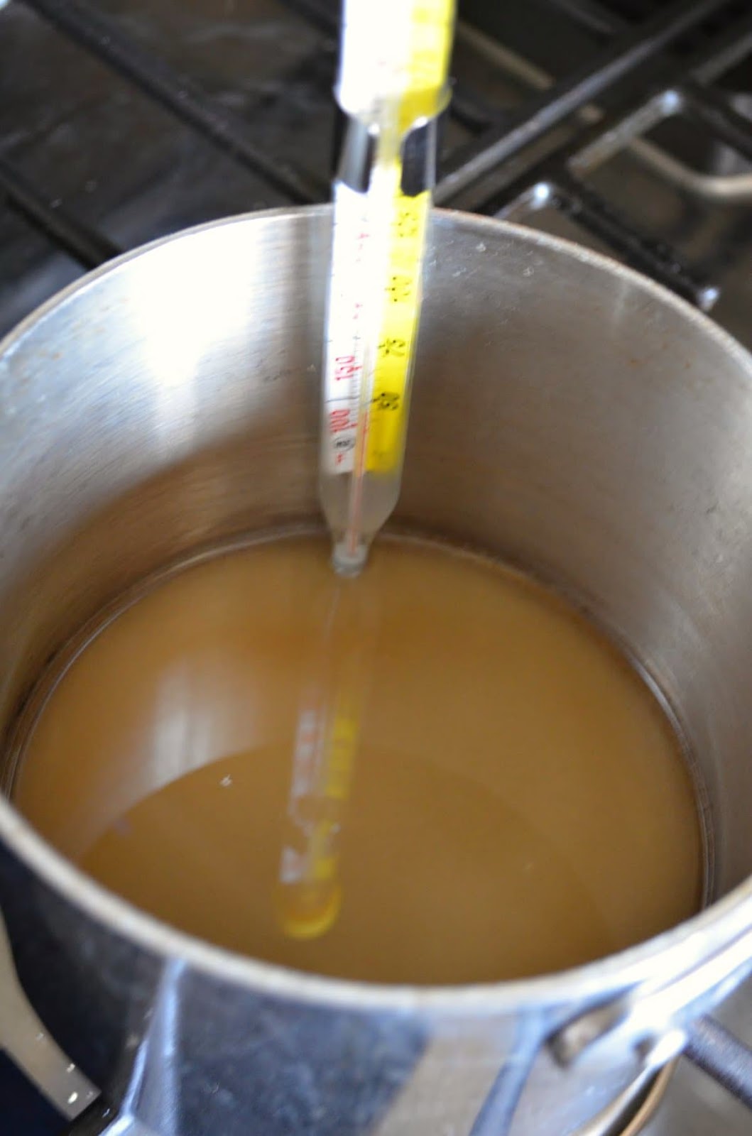 A pan filled with sugar and water and a candy thermometer attached.