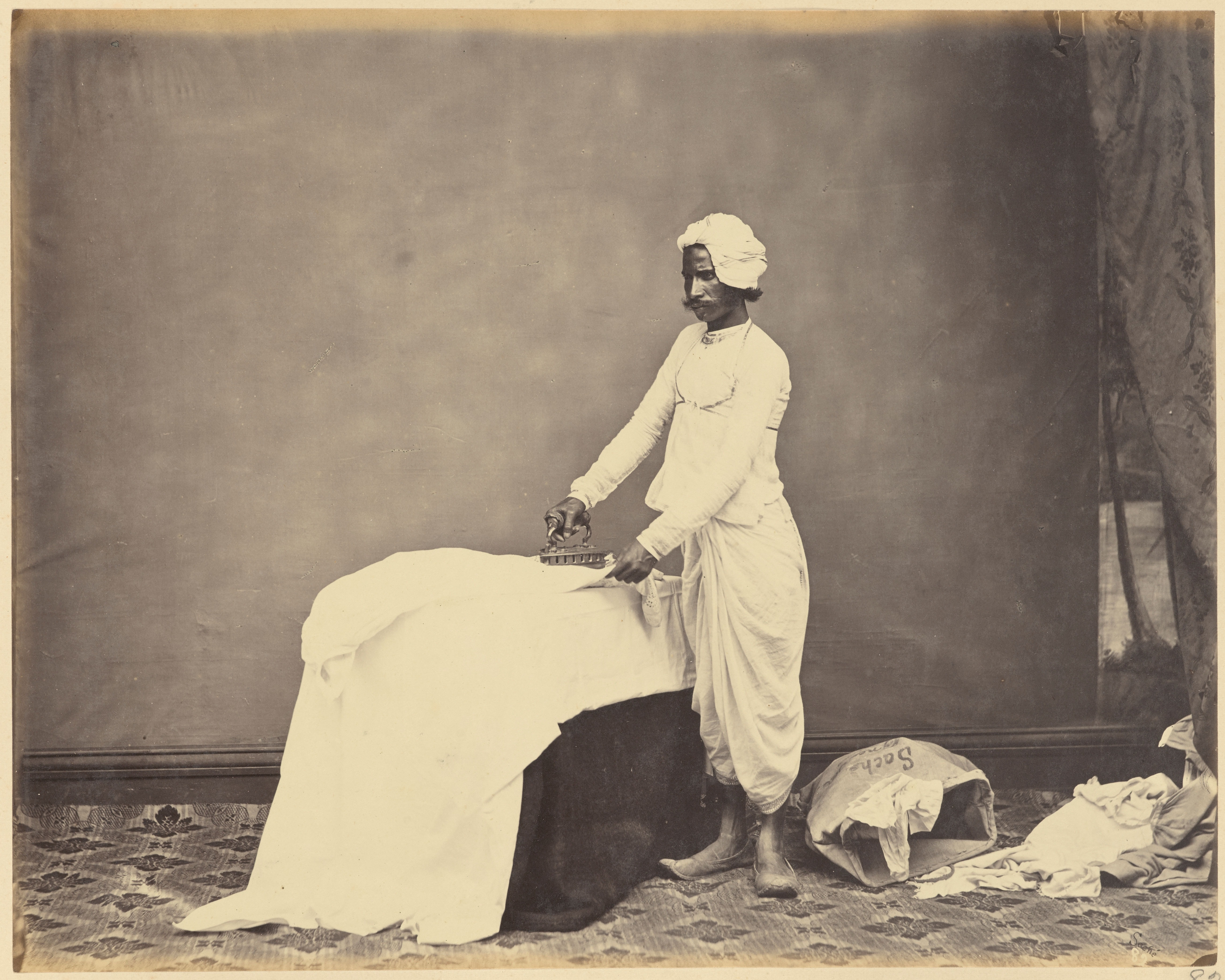 Studio Portrait Of A Man As A Dhobi, Or A Washerman, Ironing A Piece Of Fabric - Circa 1860s