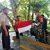 Jelang HUT RI Ke-75, Bhabinkamtibmas Bersama Babinsa Bagikan Bendera Merah Putih Kepada Warga