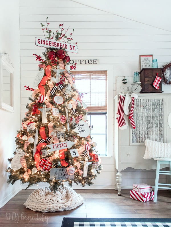 red and white cottage style tree decorated with chippy spindles, angels, red and black striped ribbon against a white shiplap wall