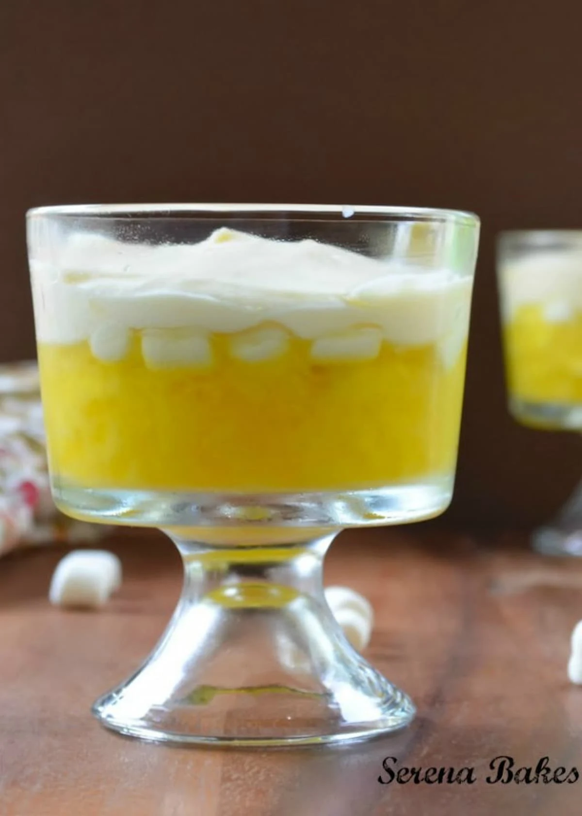 7 Up Lemon Jello Salad in a parfait cup. Layers of 7 Up Lemon Jello with Pineapple and Banana topped with Marshmallows and a Pineapple Mousse. A delicious Jello Salad Recipe.
