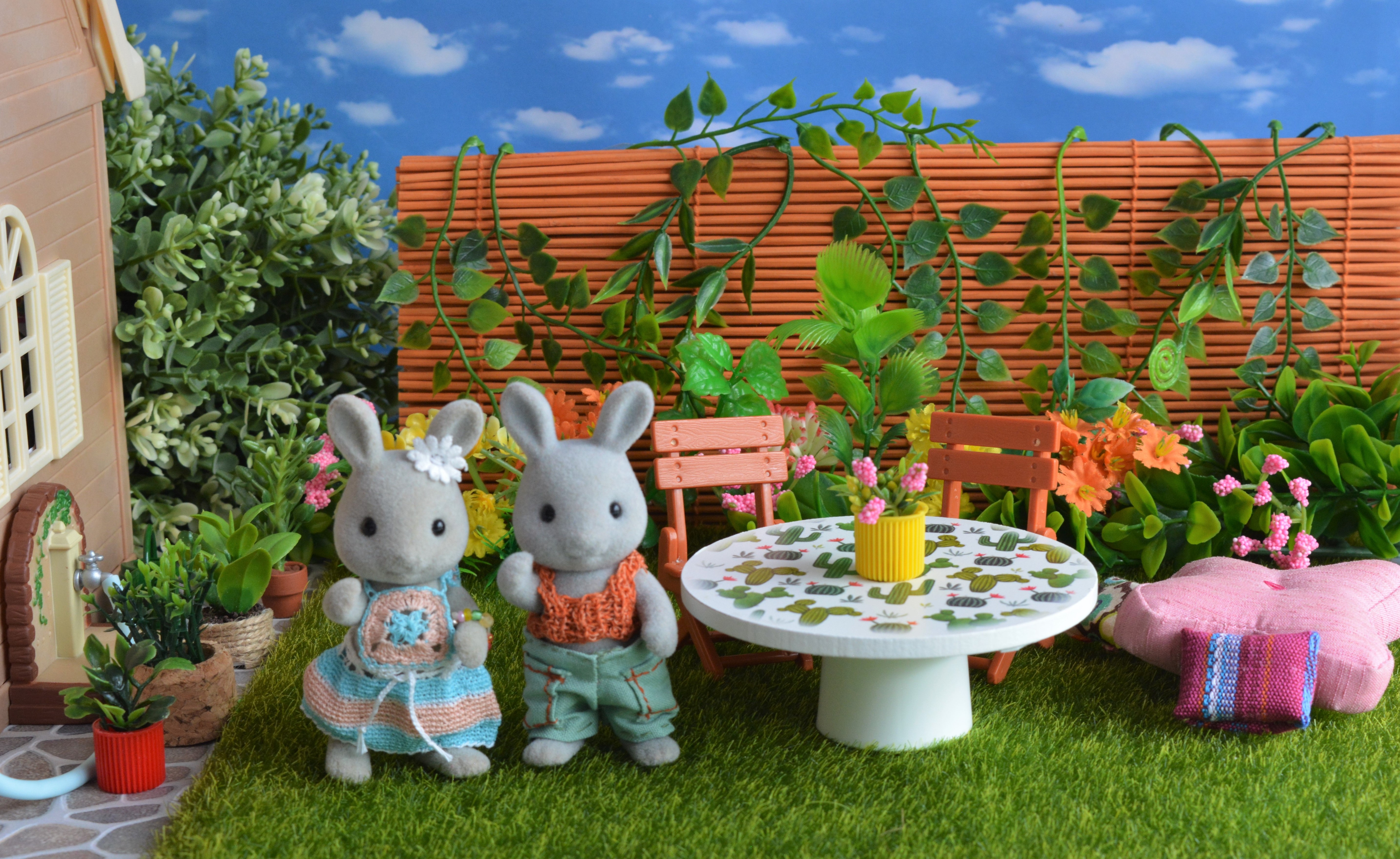 Two bunnies standing in a lush backyard full of plants and flowers.