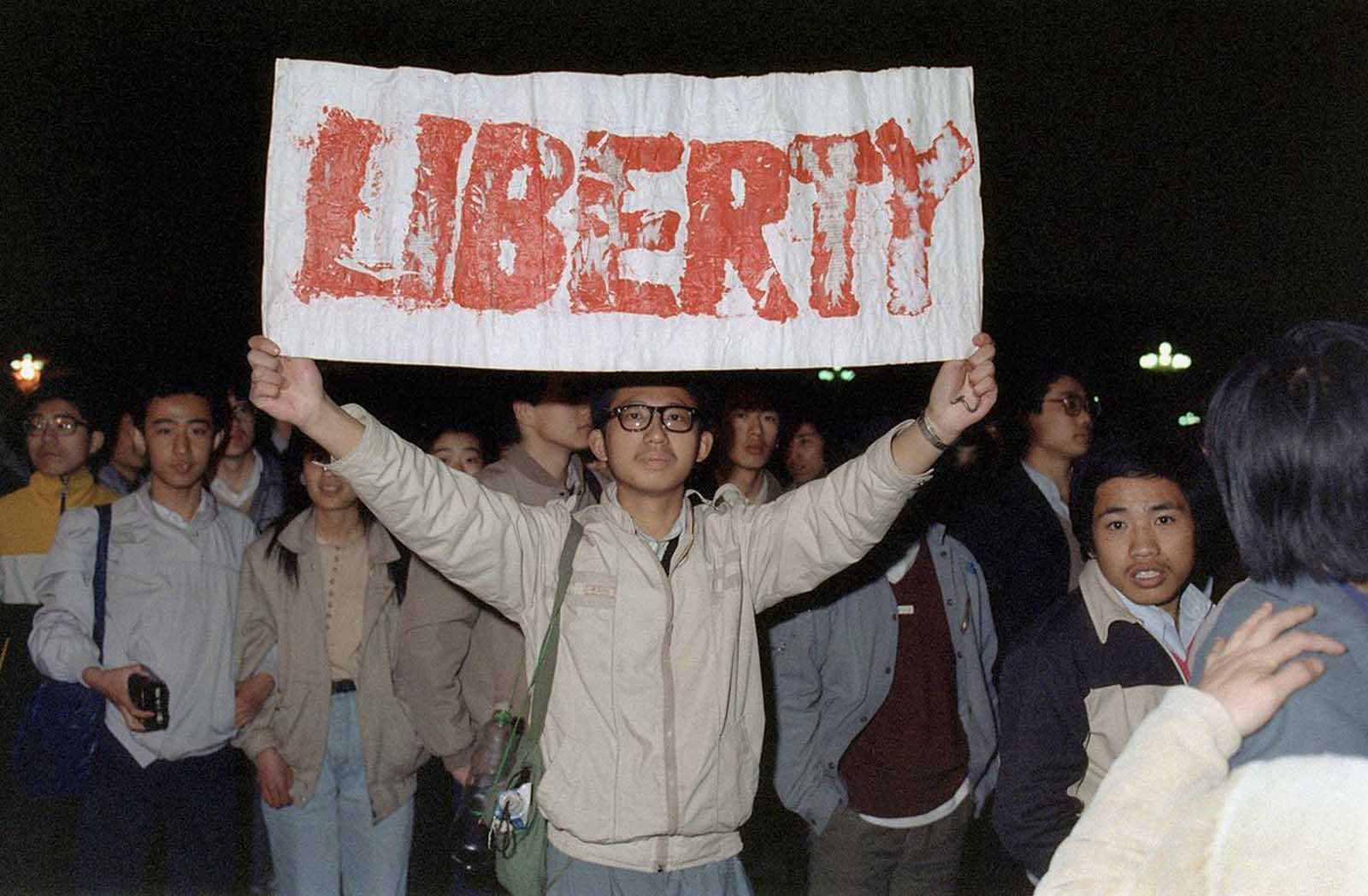 A student displays a banner with one of the slogans chanted by the crowd of some 200,000 pouring into Tiananmen Square, on April 22, 1989 in Beijing. They were attempting to participate in the funeral ceremony of former Chinese Communist Party leader and liberal reformer Hu Yaobang, during an unauthorized demonstration to mourn his death. His death in April triggered an unprecedented wave of pro-democracy demonstrations.