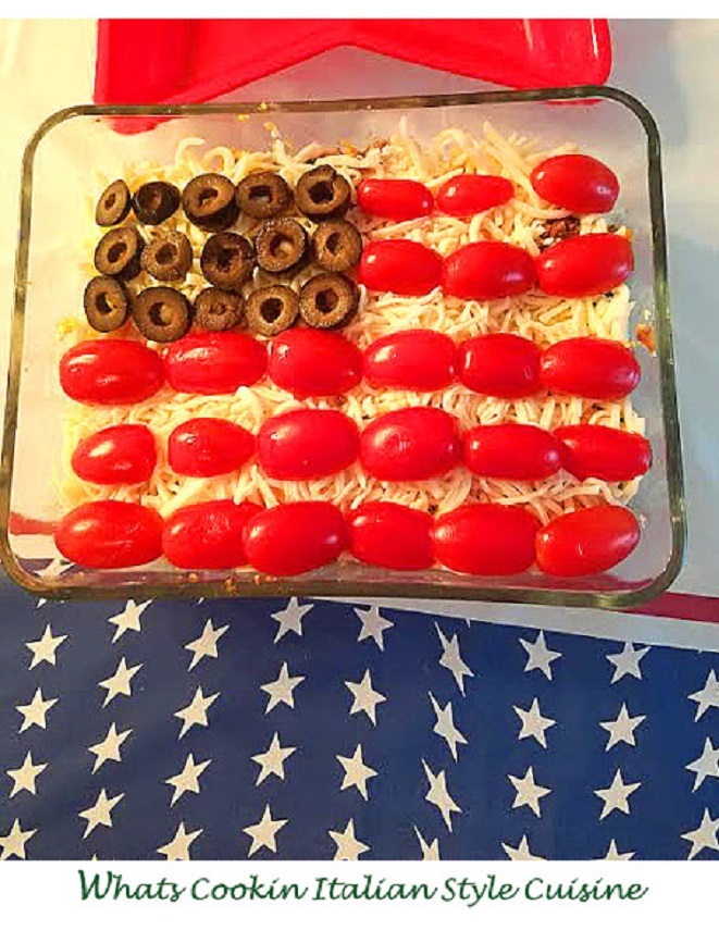 Red white and blue appetizer this is a flag shaped rectangular pan of bean dip with tomatoes and olives on top of sour cream for the 4th of July or Memorial Day Parties