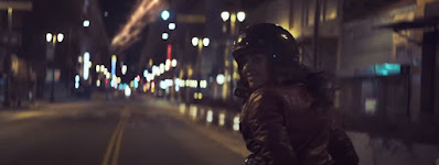 Woman riding motorcycle glances back.