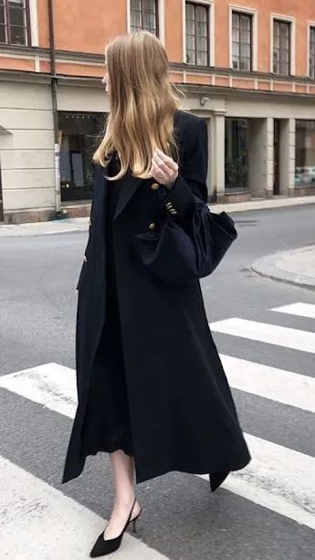 A woman wear a black coat and black dress.