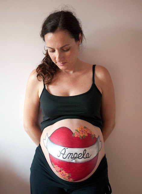 Corazón con nombre del bebé pintado en la barriga de la mamá