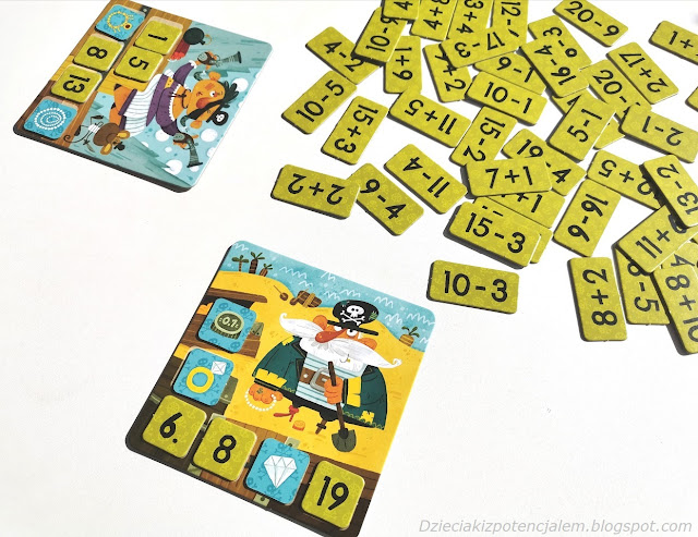 Piraci Gra matematyczna , na zdjęciu dwie plansze do gry z zakrytą już częścią wyników a między nimi leżą kafelki z działaniami odwrócone działaniem do góry aby młodszym dzieciom było łatwiej