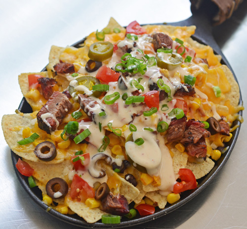 Green chile brisket nachos cooked on a Big Green Egg kamado grill.