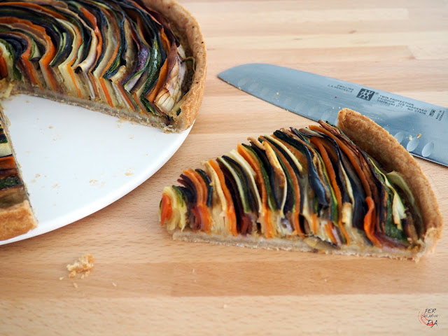 Tarta tipo quiche que alterna tiras de diferentes verduras como berenjena, calabacín, zanahorias de colores y chirivías, enrolladas en espiral, que juega con sus colores para crear un atractivo efecto final.