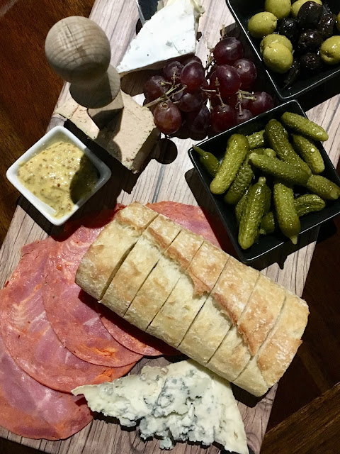 Charcuterie board with aged blue cheese, brie, capicola, pate, olives, pickles and grapes