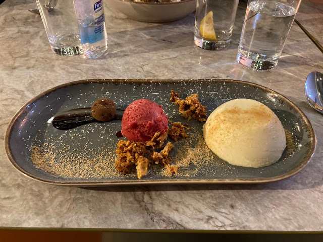 Plate of vanilla panna cotta, with raspberry sorbet and homemade cinder toffee