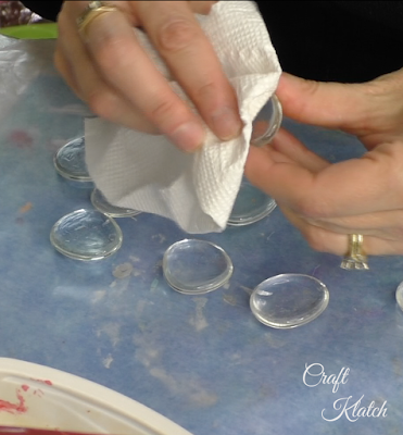 Glass gem being wiped clean with a paper towel and rubbing alcohol.