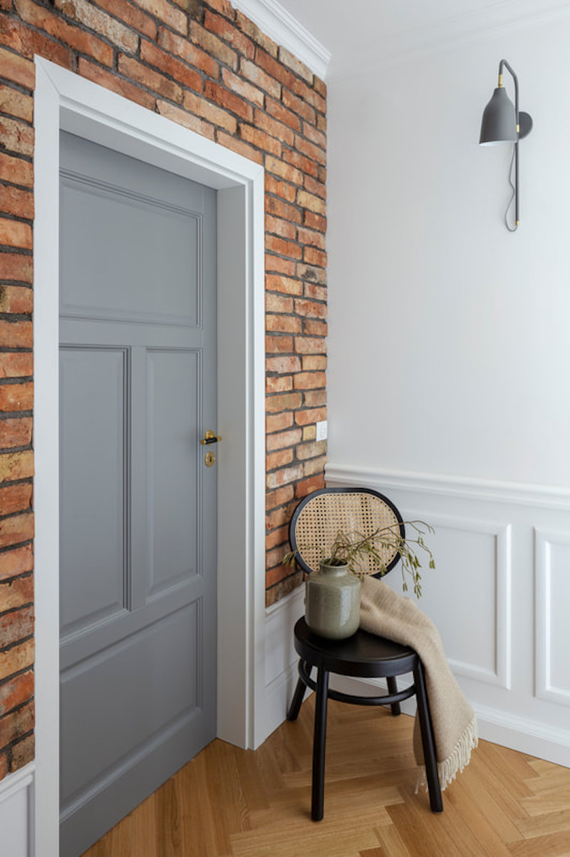 Cómo decorar con molduras y zócalos para sumar estilo a tu casa Pared de ladrillo visto y puerta con cuarterones de escayola