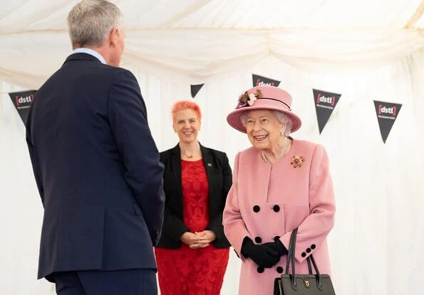 Queen Elizabeth wore a pink coat by Stewart Parvin and matching hat by Rachel Trevor-Morgan. Carved Ruby, gold and diamond brooch, Grima ruby brooch
