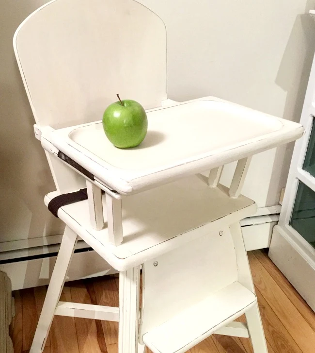 White baby high chair with green apple