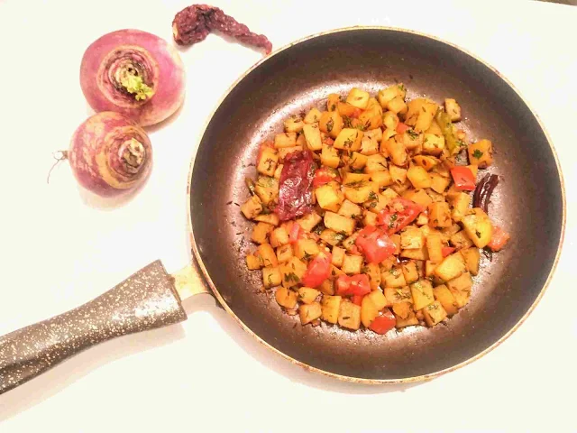 Serving spiced shalgam ( turnip) in a pan for shalgam ki sabzi, Red chilly and shalgam whole in background