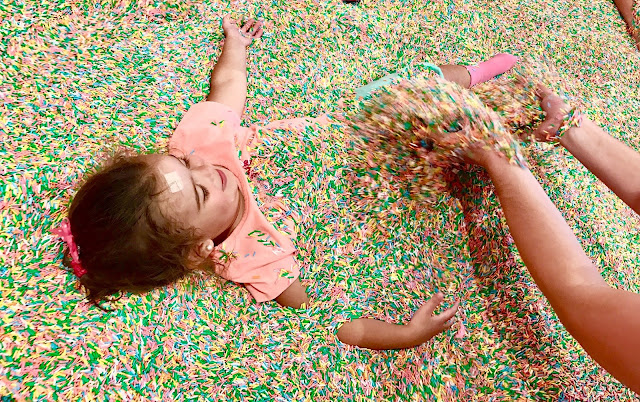 Toddler being buried in colorful sprinkles