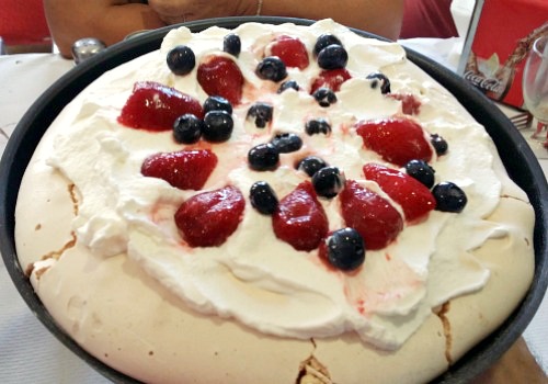 tarta de merengue francés con nata (crema de leche), fresas y arándanos