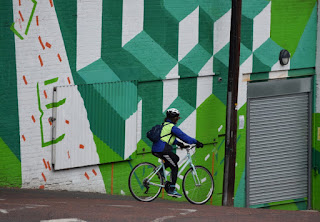 A cyclist passes a colourful building on Stepney Bank