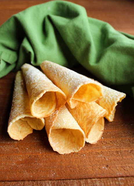 Scandinavian krumkake cookies are crunchy and delicious treats that are cooked on the stove instead of the oven. Fill them with whipped cream, fruit or frosting for an extra special dessert. golden krumkake horns dusted with powdered sugar