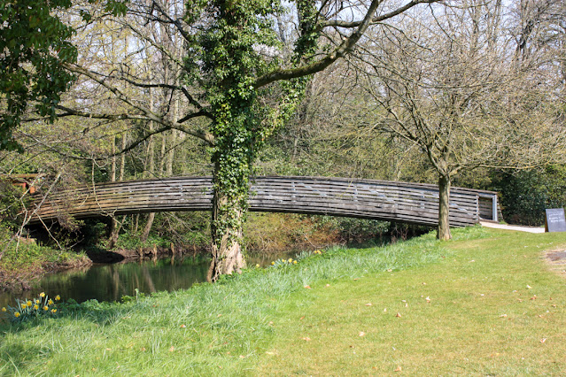 Wooden footbridge over a river, surrounded by trees.