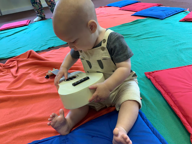 Sitting baby looking at a ukelele