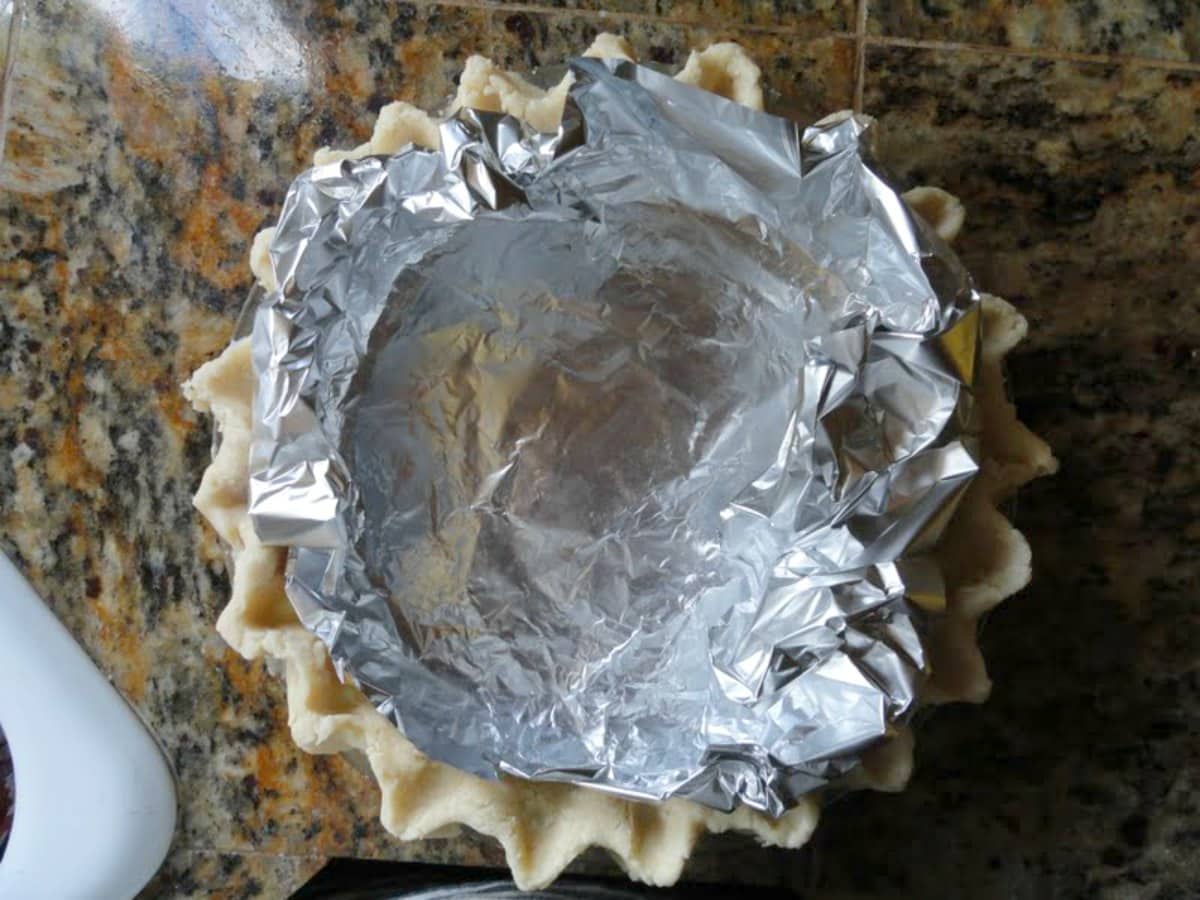 Flaky Uncooked Pie Crust in a pie plate lined with foil.