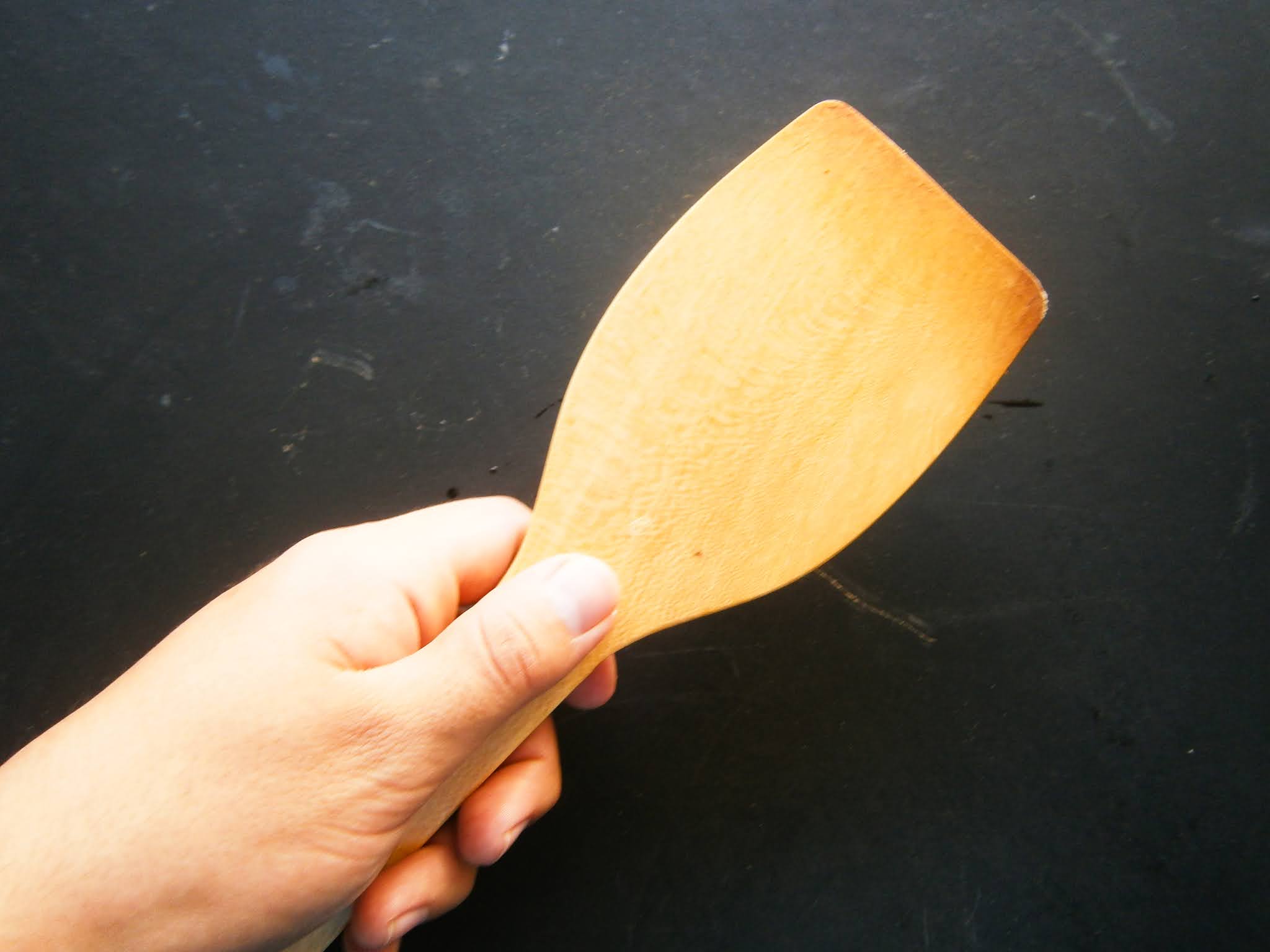 fotografía de una espatula de madera para mover comidas y guisos