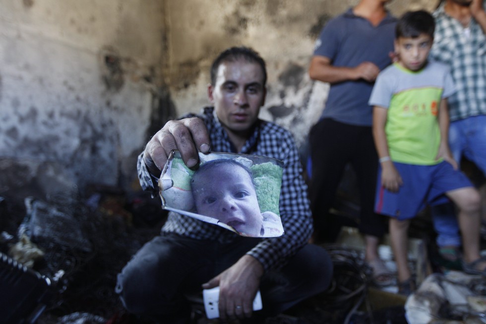 70 Of The Most Touching Photos Taken In 2015 - A relative holds a photo of 18-month-old Ali Dawabsheh. He was killed when suspected Jewish extremists threw firebombs into his family's home.