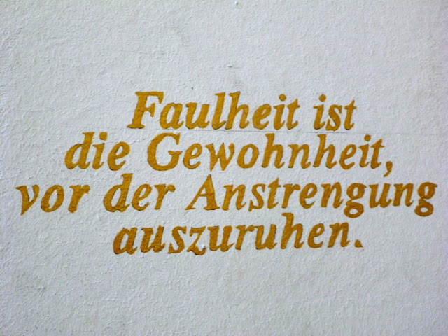 Wandinschrift: Faulheit ist die Gewohnheit, vor der Anstrengung auszuruhen.