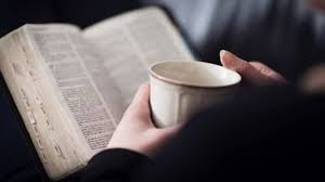 Hombre con taza de café leyendo la Biblia