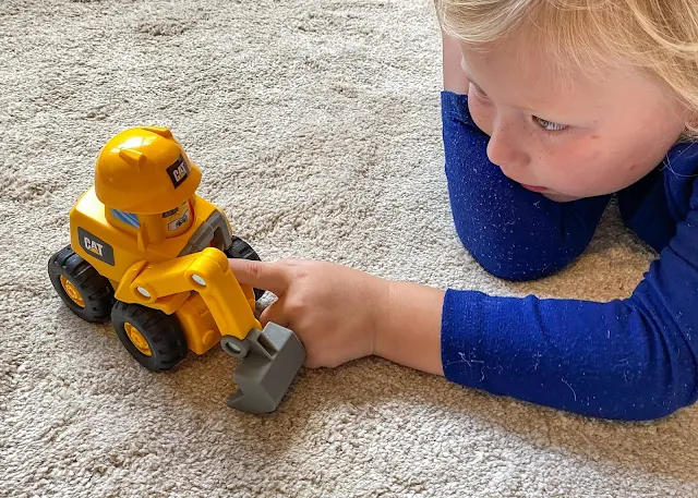 A 4 year old looking at a little cat construction digger toy