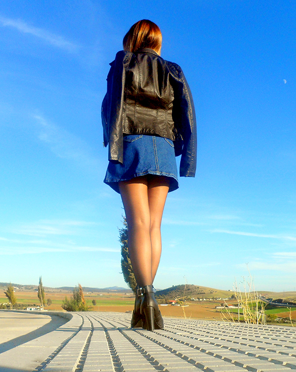 Falda denim acamapanda, jersey de punto rasgado, cazadora biker negra y botines de tacón con hebillas