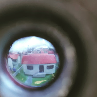 View through a peephole of a suburb of miniature white houses with red rooves.