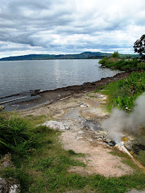 View over a lake, with a geothermal outlet pipe in the foreground.