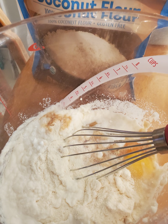 this is coconut flour in a oxo clear bowl with a whisk in it