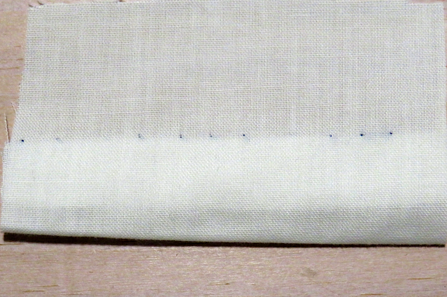 Puntada invisible con hilo azul sobre tela blanca por el derecho