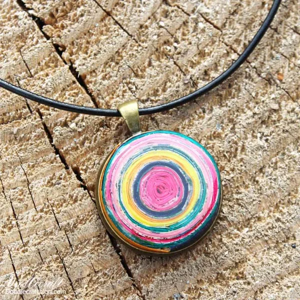 Rolled paper upcycled scrap papers pendant coated with glossy jewelry resin.