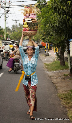 A woman carries a basket of fruit to the temple  during the Galungan festival, Bali